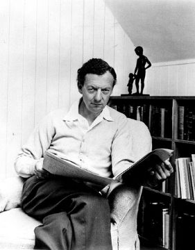 Una foto de Benjamin Britten mientras lee un periódico.
