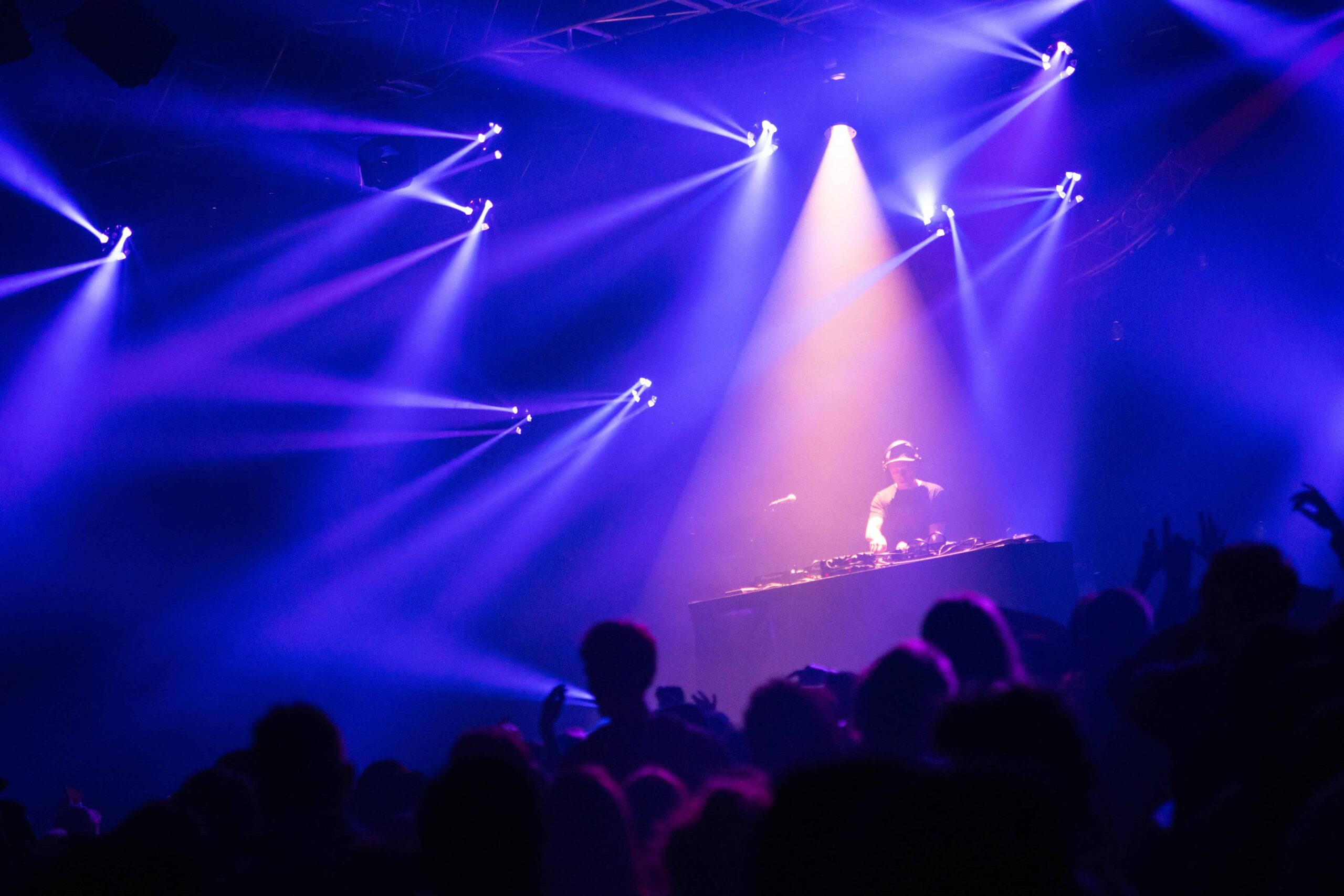Un DJ actuando en el escenario frente a una gran corona de asistentes a la fiesta