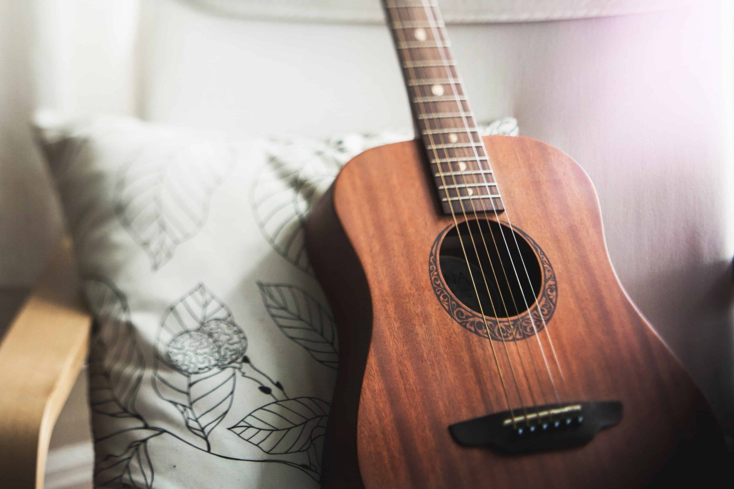 Una guitarra marrón sentada en una silla en una sala de estar