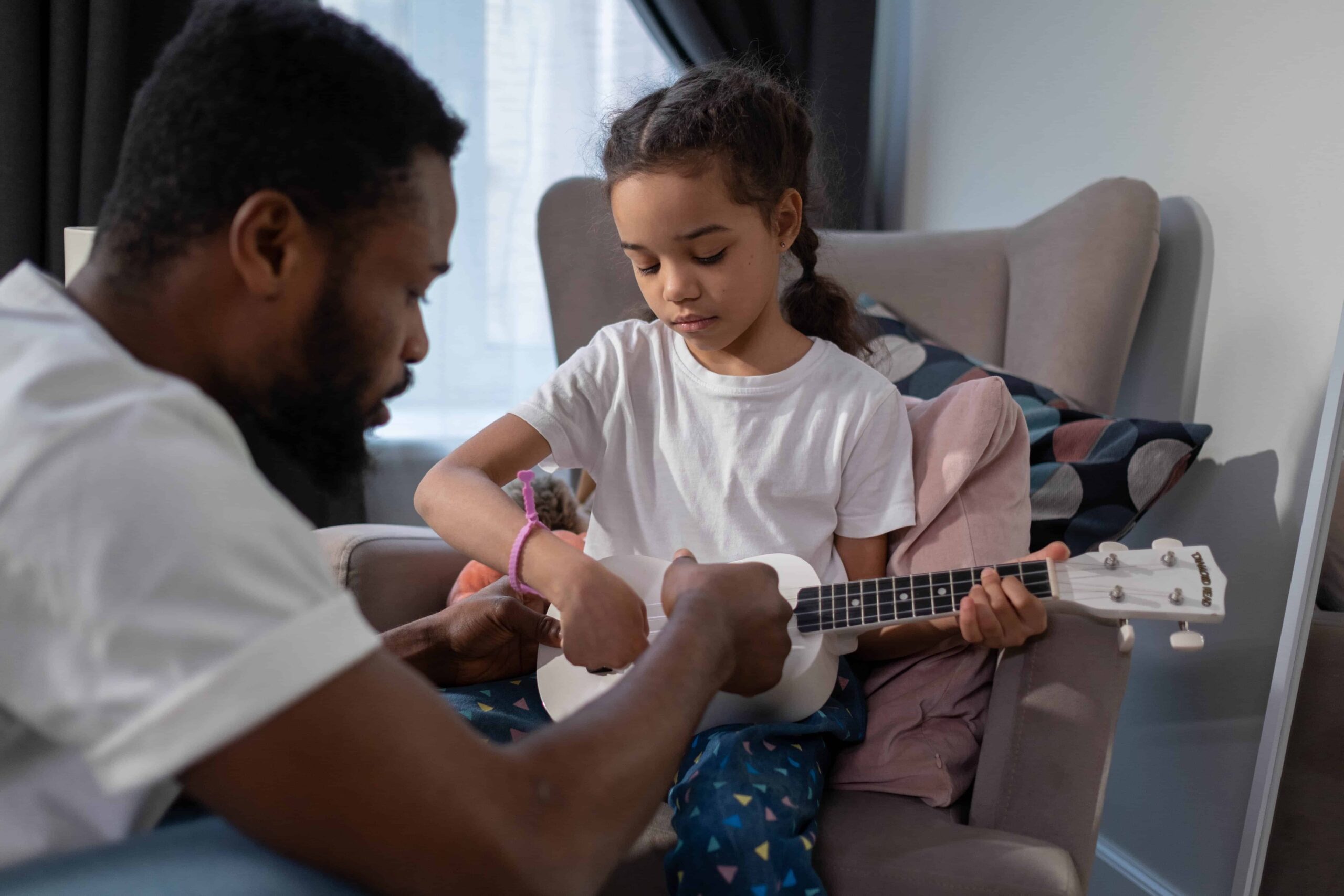 Un profesor de música enseñando a un niño a tocar un ukelele