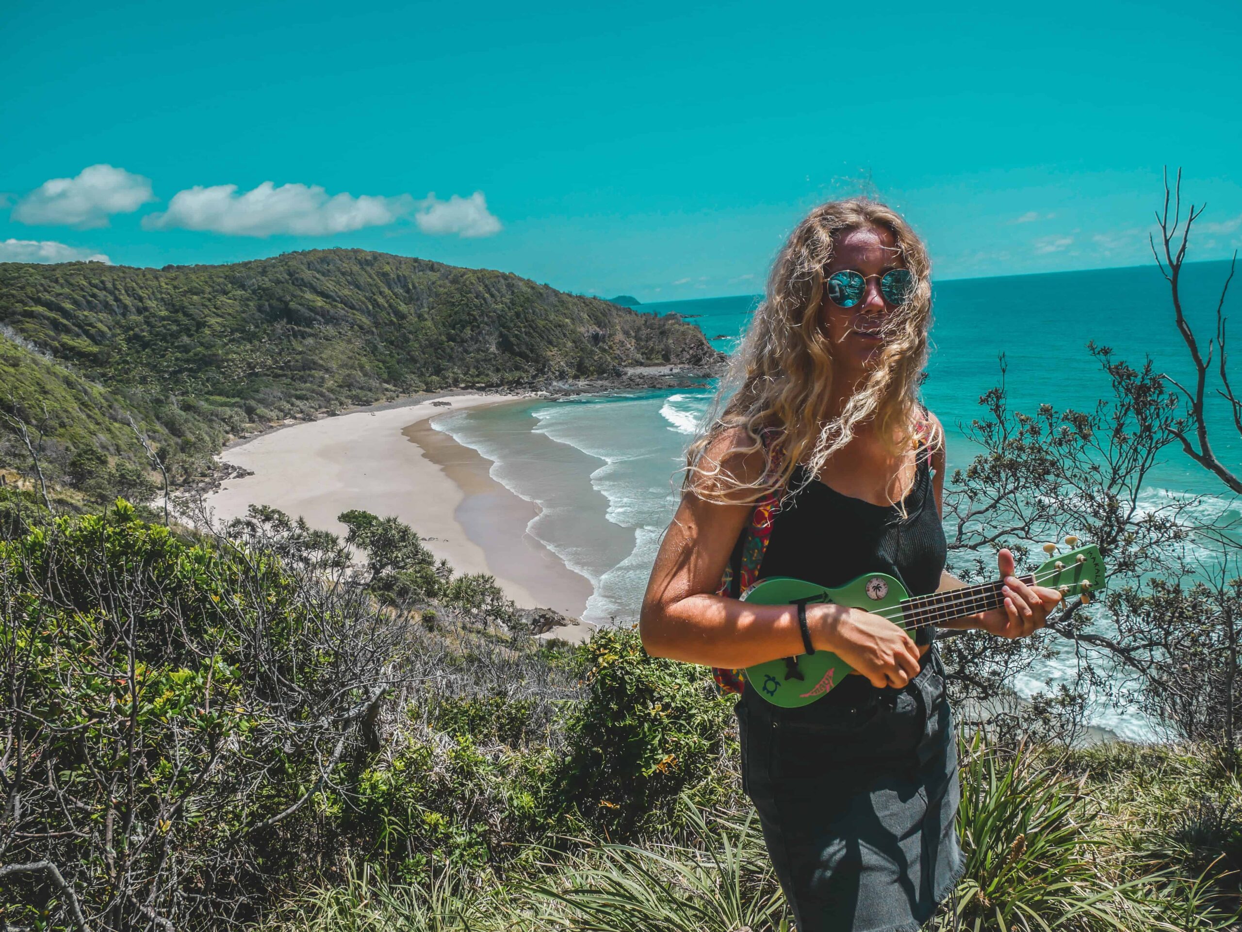 Una mujer tocando un ukelele cerca de la orilla del mar.
