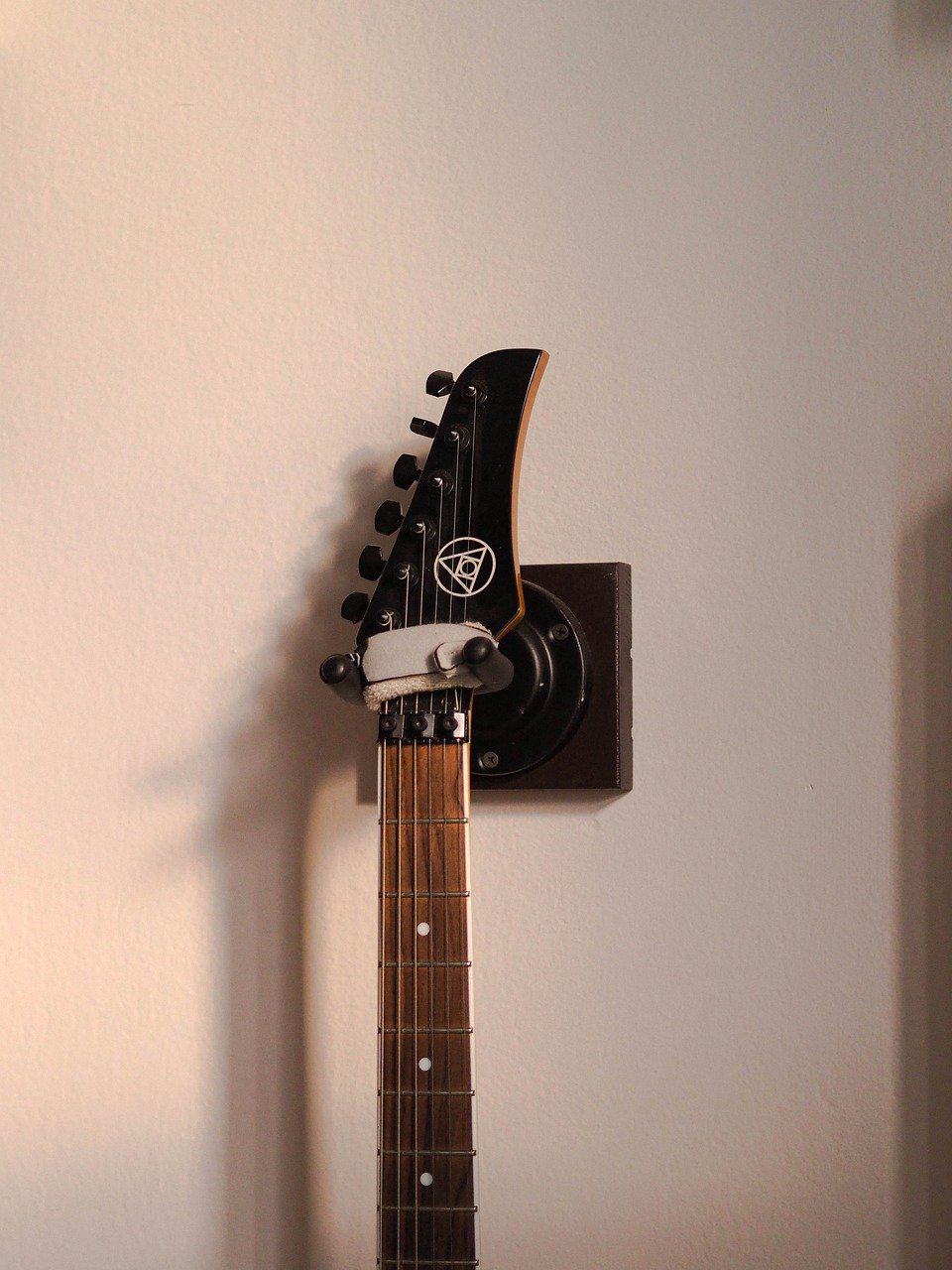 Una guitarra eléctrica está colgada de una percha de guitarra.