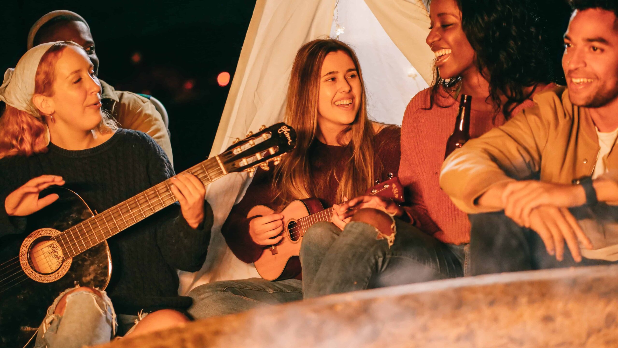 Amigos en un viaje de campamento cantando canciones y tocando guitarra y ukelele