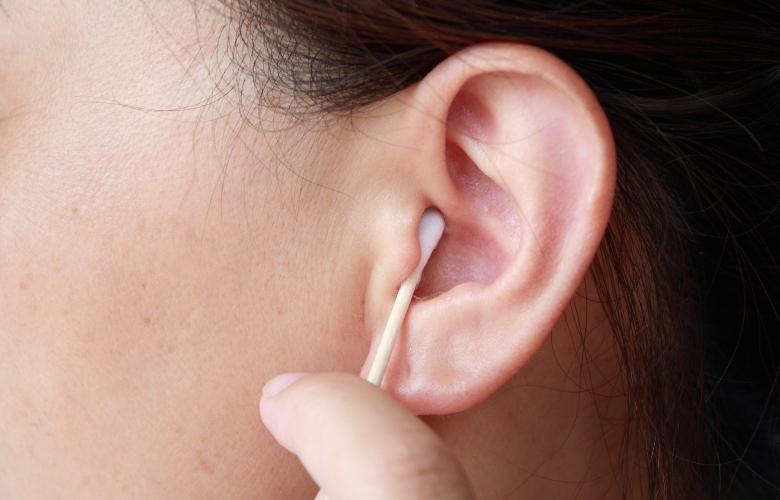 Mujer sosteniendo un hisopo de algodón y limpiando el oído